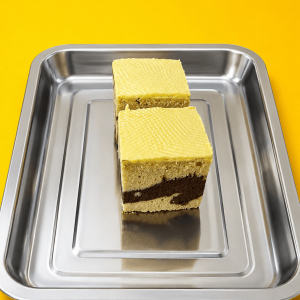 Davkem chocolate cake layered dessert with cream and chocolate filling on a stainless tray with yellow background